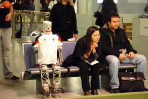 Abbildung 1: Erstmals traten beim deutschen Robocup humanoide Roboter (links) an. Wenn sie nicht gerade spielten, saßen sie unter den Zuschauern.