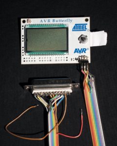 Abbildung 2: AVR Butterfly hat rechts neben dem 100-Segment-Display einen Joystick. Unten ist der Programmier-Adapter mit zusätzlichen Masseleitungen zu sehen.