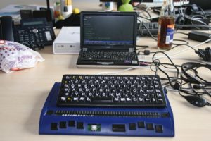 Abbildung 2: Ein Arbeitsplatz mit Braillezeile (blau) und Linux-Laptop. Über den Kopfhörer liest der Screenreader die Anzeige vor, hier Lynx auf einer OTRS-Seite.