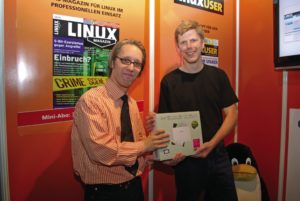Abbildung 1: Linux-Magazin-Leser Heiko Besemann (rechts) nutzte den Linuxtag, um seinen Gewinn, einen Eee-PC mit vorinstalliertem Linux, in Empfang zu nehmen. Redakteur Nils Magnus gratulierte dem Entwickler aus Itzehoe, der die meisten Antworten im Linux-Rätsel korrekt beantwortet hatte. Besemann, in seinem Job von Windows-Entwicklern umgeben, freute sich: &bdquo;Als Python-Fan kommt ein Linux-Subnotebook natürlich sehr gelegen.&ldquo; Er sagte zu, der Redaktion von seinen Erfahrungen mit dem Winzling von Asus zu berichten.