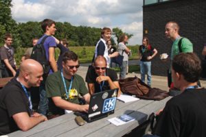 Abbildung 2: KDE-Projektler Frank Karlitschek, Sebastian Kügler und Franz Keferböck (von links nach rechts) im Kreise anderer Konferenzteilnehmer auf der Cafeteria-Terrasse während einer Vortragspause.