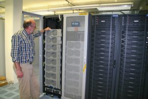 Abbildung 3: Zwei Racks beherbergen 960 Opteron-Kerne und knapp 4 TByte Hauptspeicher. Maschinensaalleiter Hans Mayr zeigt, wo unter SLES die wissenschaftlichen Anwendungen die eigentliche Modellrechnung steuern.